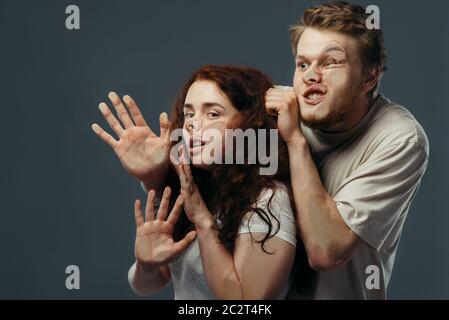 Giovane coppia facce schiacciate su vetro trasparente, divertente emozione. Uomo e donna con grimaci pressati in piedi alla vetrina, umorismo, loo scomodo Foto Stock