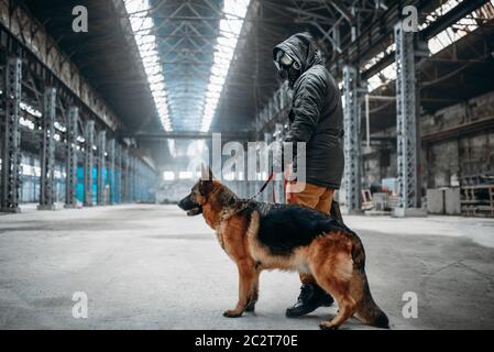 Stalker soldato in maschera a gas e cane in edificio abbandonato, sopravvissuti dopo la guerra nucleare. Mondo apocalittico. Post-apocalypse lifestyle su rovine, fare Foto Stock