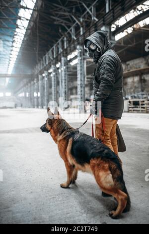 Stalker soldato in maschera a gas e cane in edificio abbandonato, sopravvissuti dopo la guerra nucleare. Mondo apocalittico. Post-apocalypse lifestyle su rovine, fare Foto Stock