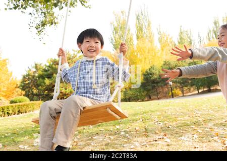 Felici i bambini sulle altalene nel parco Foto Stock