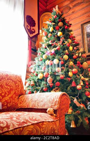 Interno di chalet in legno con albero di natale e divano Foto Stock