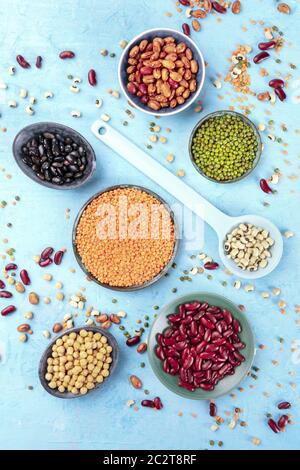 Legumi, overhead shot su uno sfondo blu. Gli impulsi di vivaci tra cui colorato fagioli, lenticchie, ceci, una composizione flatlay Foto Stock