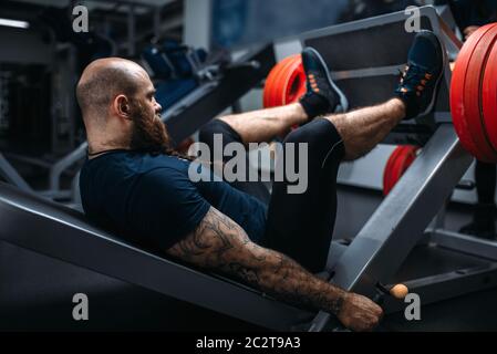 Forte atleta sulla macchina ginnica con barbell, formazione in palestra. Uomo Barbuto in allenamento in sport club, uno stile di vita sano Foto Stock