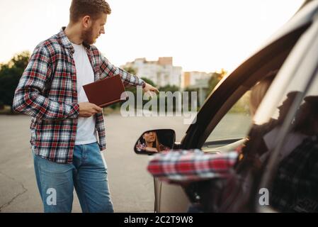 L'istruttore maschile prende l'esame, la studentessa femminile sul terreno di guida, il concetto di scuola di automobile. Test per principianti Foto Stock