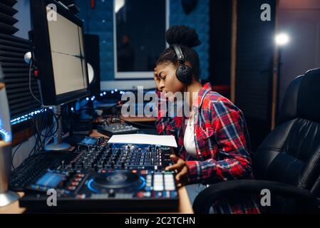 Suono femmina operatore che lavora presso il pannello di controllo remoto audio in studio di registrazione. Musicista al mixer professionale di miscelazione di musica Foto Stock