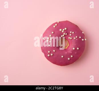 Rotondo rosso ciambella con spruzzi di colore bianco su uno sfondo rosa, vista dall'alto Foto Stock