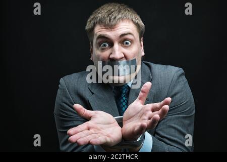Imprenditore con bocca e mani coperte da nastro adesivo impedendo discorso, studio shoot Foto Stock