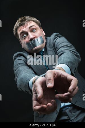 L'uomo con la bocca e le mani coperti da nastro adesivo, studio shoot Foto Stock