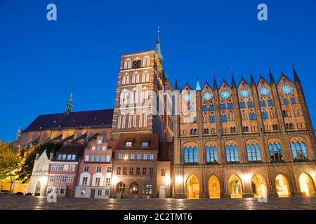 Stralsund, Germania. 15 giugno 2020. Vista della chiesa di San Nikolai e del municipio (r) all'ora blu. I dischi di gioielleria parzialmente placcati in oro, circa 80 kg, sono stati realizzati intorno al 1880 secondo il modello tardo medievale. Si presume che i dischi delle stelle simboleggino il regno dei cieli, che come ordine divino si trova sopra l'ordine terreno, umano - il municipio con il suo consiglio. Il municipio di Stralsund, patrimonio dell'umanità, è uno dei più importanti edifici secolari anseatici della regione del Mar Baltico. Credit: Stefan Sauer/dpa-Zentralbild/dpa/Alamy Live News Foto Stock