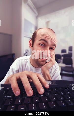 Stanco indifferente uomo al lavoro con il computer ti guarda Foto Stock