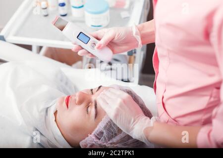 Medico che fa la procedura medica con la pelle del viso. Terapia di pulizia ad ultrasuoni. Trattamento cosmetologico. Salute. Foto Stock