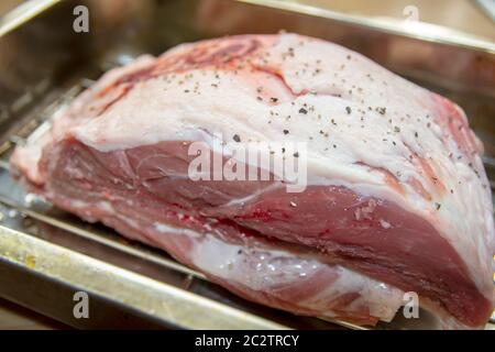 Un piccolo giunto di agnello pronto su una rastrelliera in una padella da tostare in forno Foto Stock