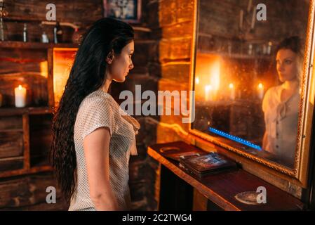 Giovane donna allo specchio su seance spirituale, stregoneria. Femmina chiamate foreteller gli spiriti, magic Foto Stock