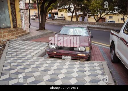 Abha / Arabia Saudita - 23 gennaio 2020: Auto rossa vecchia e arrugginita parcheggiata sulla strada Foto Stock