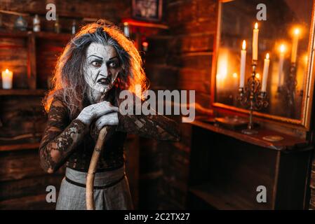 Scary strega con una canna a specchio e candele, poteri oscuri di stregoneria, seance spirituale. Femmina chiamate foreteller gli spiriti, terribile fortune Foto Stock