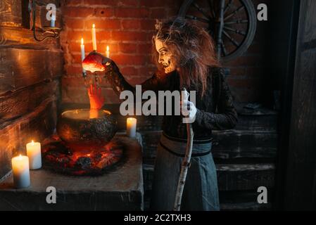 Scary witch legge scrivi sulla pentola con parti del corpo umano, poteri oscuri di stregoneria, seance spirituale con le candele. Femmina chiamate foreteller la spir Foto Stock