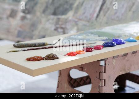 Vernice ad olio multicolore, pennello per artisti e un coltello per palette su un tavolo di legno Foto Stock