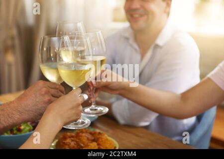 Mani di un gruppo di persone che si acclamano con il vino bianco Foto Stock