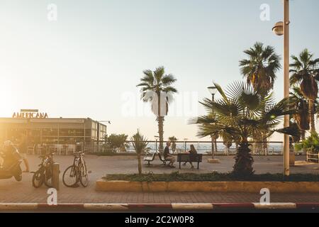 Tel Aviv/Israel-13/10/18: Una coppia seduta sulle panchine, mantenendo la distanza, sul terrapieno di Tel Aviv, socializzando in una serata estiva solo b Foto Stock