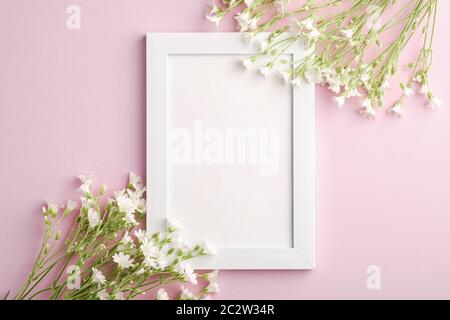 Bianco mockup cornice foto vuota con mouse-orecchio fiori di ceci su sfondo rosa, vista dall'alto spazio copia Foto Stock