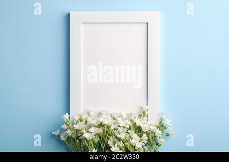 Bianco mockup cornice foto vuota con mouse-orecchio fiori di ceci su sfondo blu, vista dall'alto spazio copia Foto Stock