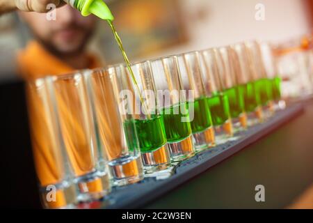 Preparazione di cocktail cosmopoliti verdi. Bevanda alcolica verde in bicchieri al bar. Concetto di alcool d'elite. Foto Stock