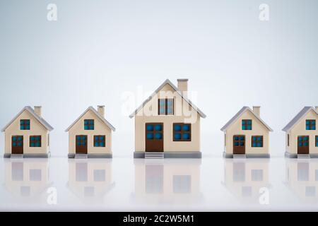 Una piccola e splendida modelli della casa di disporre in una fila su tavola riflettente Foto Stock