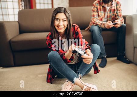 Happy amici con joystick riproduce video console a casa. Un gruppo di giocatori che giocano videogioco, maschio e femmina i giocatori hanno un concorso Foto Stock