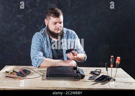 Maschio di ingegnere informatico che fissa il problema con il computer portatile. Dispositivi elettronici La tecnologia di riparazione Foto Stock