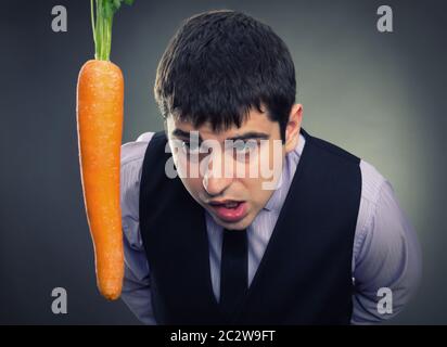 La metafora di esca. Uomo che guarda la carota Foto Stock