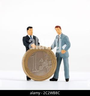 Statuine in miniatura di imprenditori con una moneta in euro Foto Stock