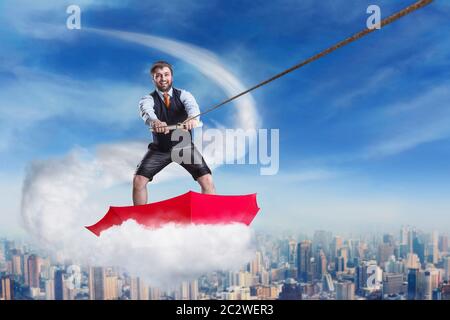 Imprenditore di successo è il surf in ombrello sul cloud contro downtown Foto Stock