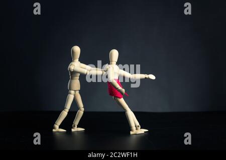 Coppia di figure di legno, uomo che disperde donna su nero Foto Stock