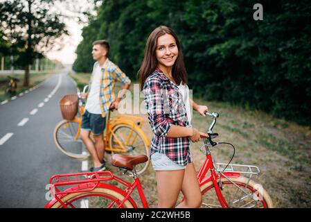 Giovane uomo e donna si pone con moto retrò. Coppia su biciclette d'epoca. Vecchi cicli, data romantica Foto Stock