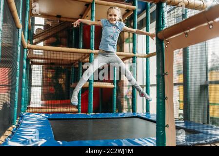 Funny Girl saltando sul trampolino, bambini Game center. Emozionato bambino divertirsi sul parco giochi al chiuso. Capretto femmina giocando in un centro divertimenti Foto Stock