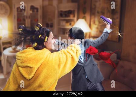 La donna in vestaglia batte il marito baro con pan per infedeltà Foto Stock