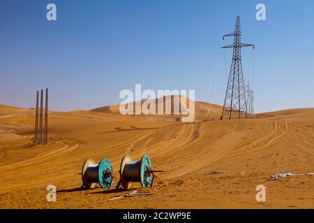 Tralicci elettrici con i loro cavi ad alta tensione installati per trasportare l'energia da una sottostazione di elettricità a un nuovo impianto petrolifero nel deserto del Sahara. Foto Stock