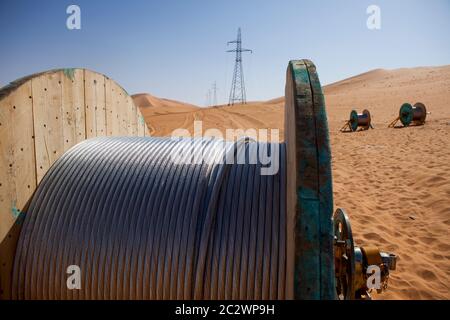 Tralicci elettrici con i loro cavi ad alta tensione installati per trasportare l'energia da una sottostazione di elettricità a un nuovo impianto petrolifero nel deserto del Sahara. Foto Stock