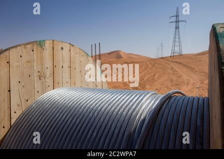 Tralicci elettrici con i loro cavi ad alta tensione installati per trasportare l'energia da una sottostazione di elettricità a un nuovo impianto petrolifero nel deserto del Sahara. Foto Stock