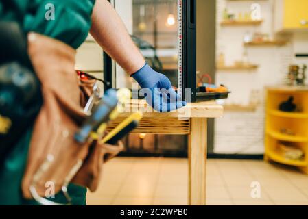 Repairman in uniforme le riparazioni frigorifero a casa. La riparazione di un frigorifero con occupazione, professional service Foto Stock