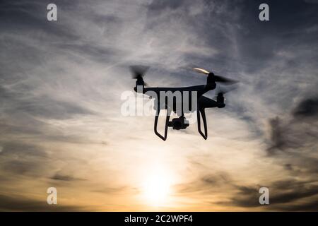 Silhouette di un drone in volo al tramonto Foto Stock