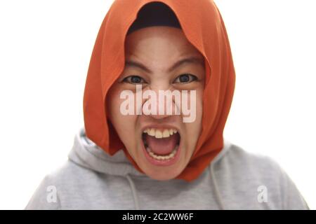 Arrabbiato musulmano ragazza in hijab urlando forte, primo piano ritratto su sfondo bianco Foto Stock