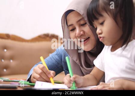 Madre musulmana asiatica che disegnano con sua figlia, mamma single che insegna bambina, concetto di famiglia felice Foto Stock