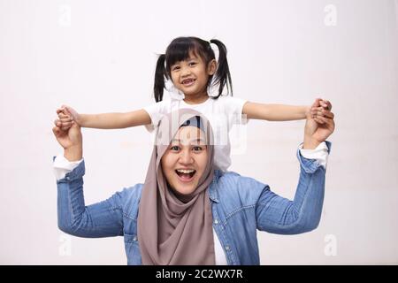 Madre musulmana che indossa hijab sorridente mentre gioca con la sua bambina, mamma e figlia si amano l'un l'altro, felice singolo genitore Foto Stock