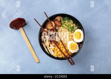 Ramen. Soba zuppa con uova, funghi e ortaggi, ripresa dall'alto con il tradizionale cucchiaio di legno e bastoncini Foto Stock