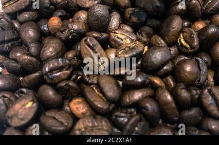 Grande gruppo di materie Roasted Brown i chicchi di caffè immagazzinato in un contenitore e quindi la massa. Sfocate e profondità di campo. Vista ravvicinata. L'agricoltura un Foto Stock