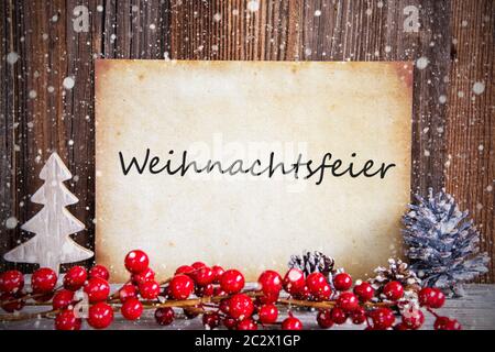 Carta con testo in tedesco significa Weihnachtsfeier festa di Natale. Decorazione di natale e lo sfondo di legno con la neve Foto Stock