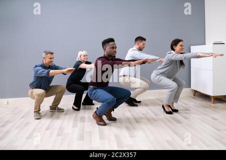 Sorridente multi etnico giovani imprenditori facendo sit ups insieme al lavoro Foto Stock