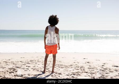 Giovane uomo da corsa misto in piedi sulla spiaggia Foto Stock