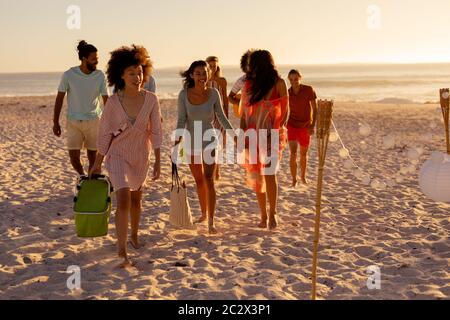 Gruppo di amici di corsa misti che cammina sulla spiaggia Foto Stock